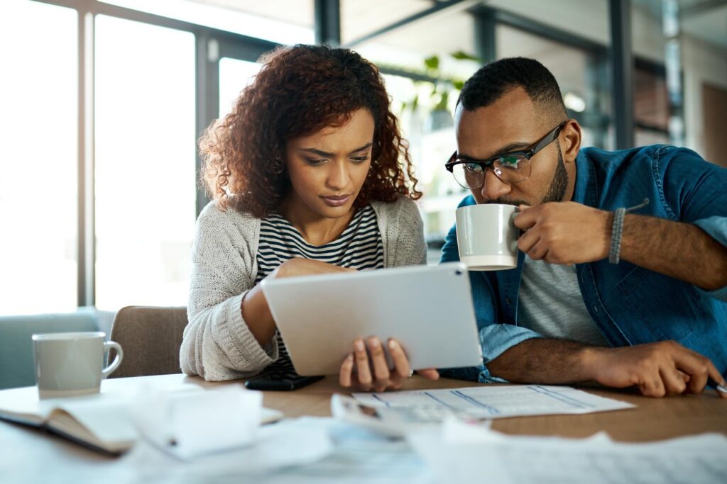 Tablet, news or couple with financial budget, investment growth or planning savings online on website. Coffee, interest rates or people reading on recession for bills, inflation or household expenses