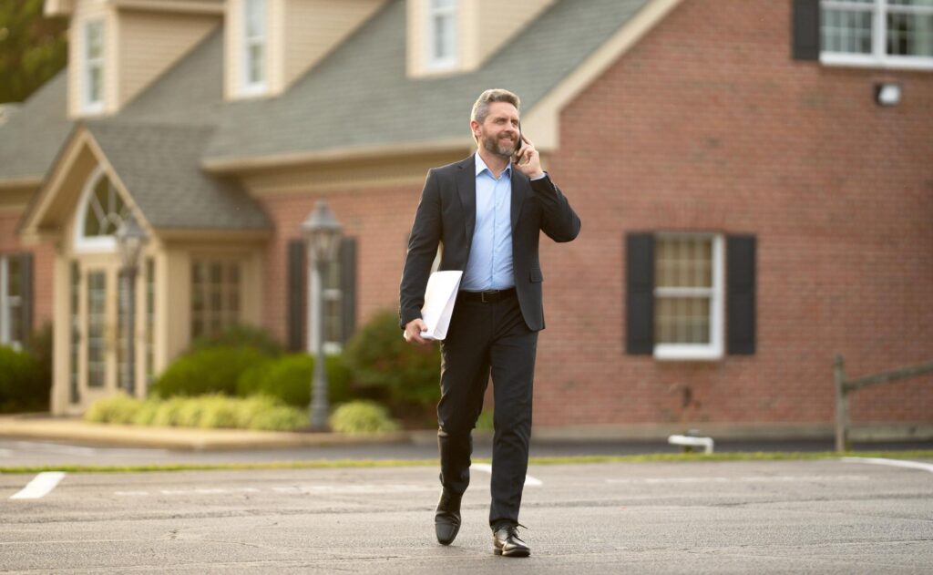 Real estate agent poses confidently in front of building ready for sale. Real estate entrepreneur closing deal. Real estate agent buying house. Realtor shows apartment. Real estate agent near building.