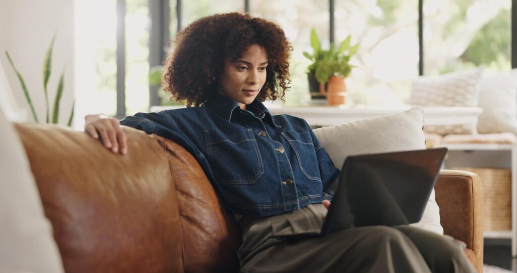 Laptop, home and black woman on sofa for online editing, story review and freelance career. House, remote worker and person on couch with computer for digital submission, copywriting and planning
