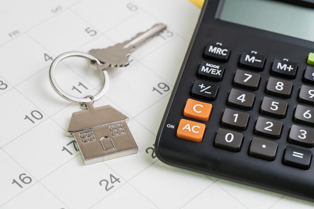 New house purchase, mortgage schedule reminder or real estate payment day, silver house keyring with calculator on white clean calendar