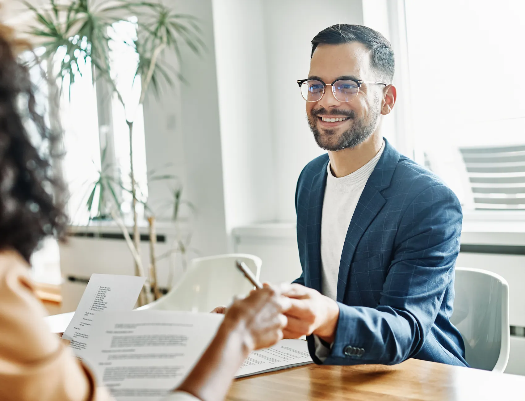 A property manager in Arkansas hands over a pen to a new tenant who is signing the lease.