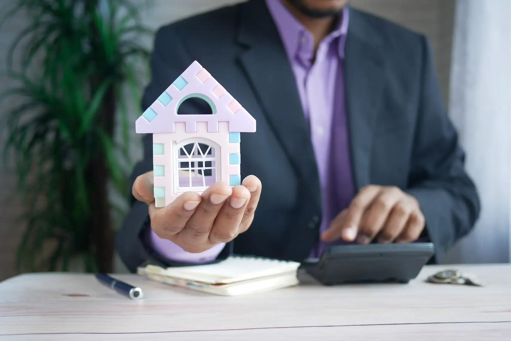 A property manager in South Carolina is shown holding a small model house.