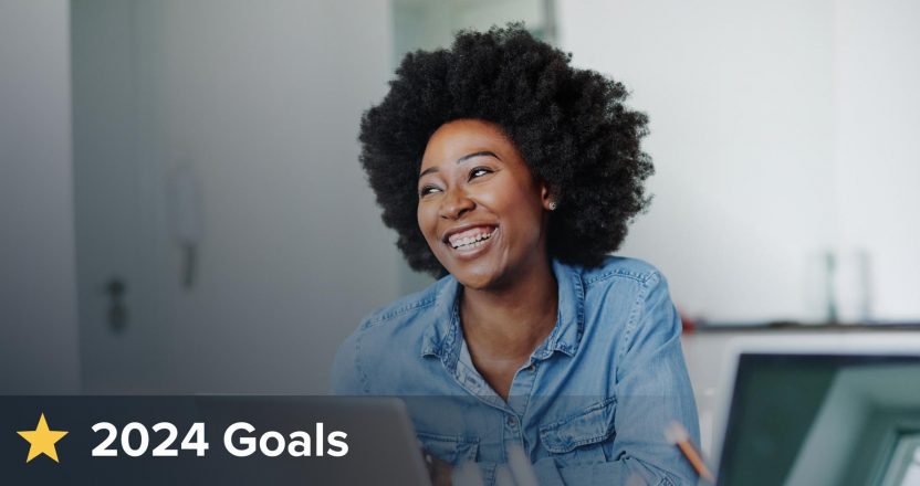 A smiling woman at a laptop beside a 2024 Goals banner, planning her real estate investment strategy.