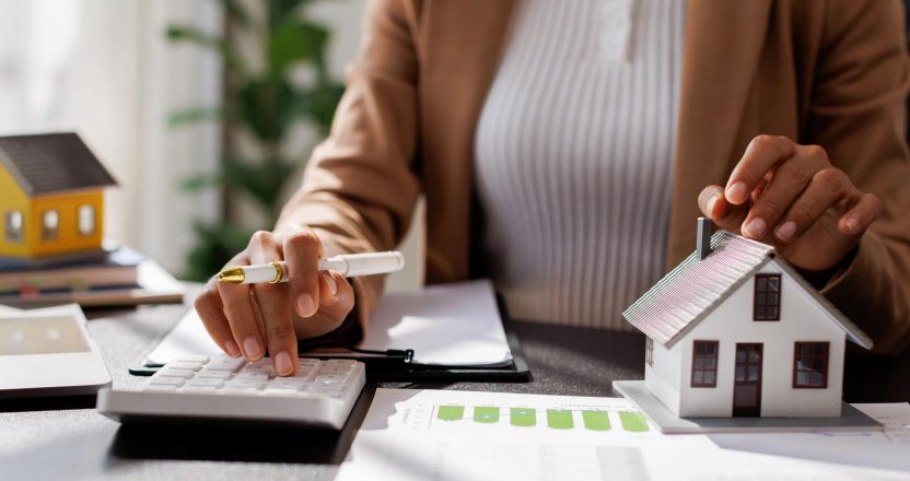 Business mortgage realtor with house model, sitting at desk, real estate agent manager working on calculator and documents, mortgage and property.