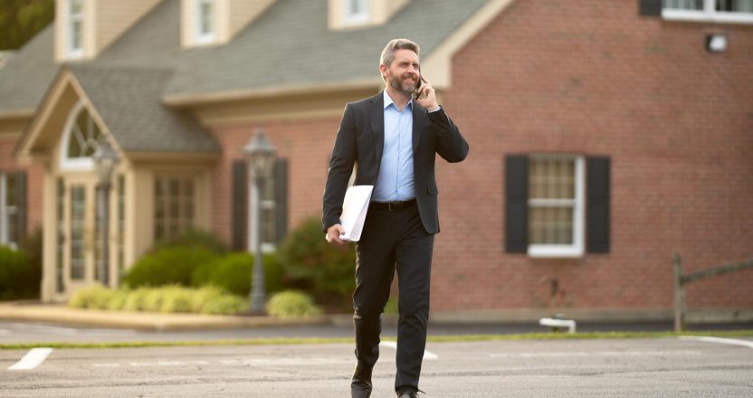 Real estate agent poses confidently in front of building ready for sale. Real estate entrepreneur closing deal. Real estate agent buying house. Realtor shows apartment. Real estate agent near building.