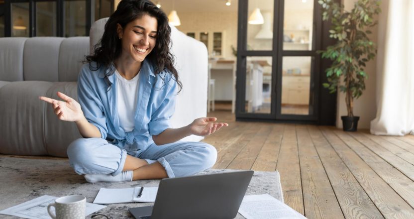Portrait of cheerful young woman making video call, using laptop, communicating online from home, copy space