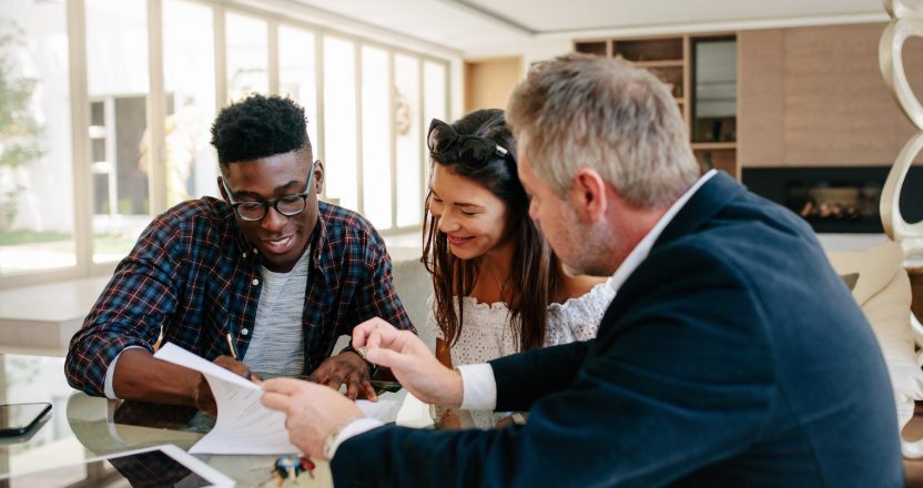 Couple in real estate agency signing property contract documents