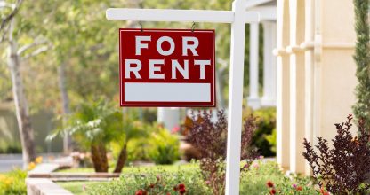 Red For Rent Real Estate Sign in Front House.