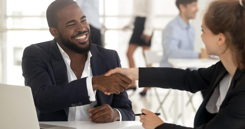 Happy african manager broker handshaking caucasian client at meeting