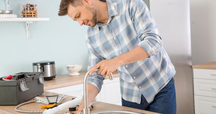 Plumber installing sink in kitchen
