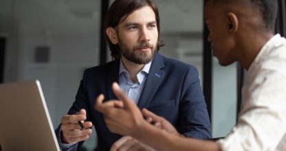 Focused businessman listening to young african american employee.