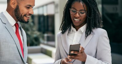 Excited happy colleagues looking at mobile phone screen