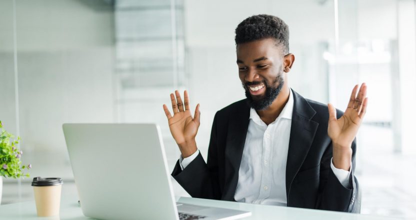 Shocked african american businessman in suit feeling stunned by online news looking at computer screen sitting at workplace with laptop, stressed trader investor surprised by stock market changes
