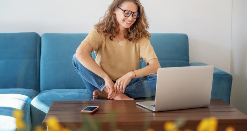 Charming beautiful young girl in glasses with curly hair sits on