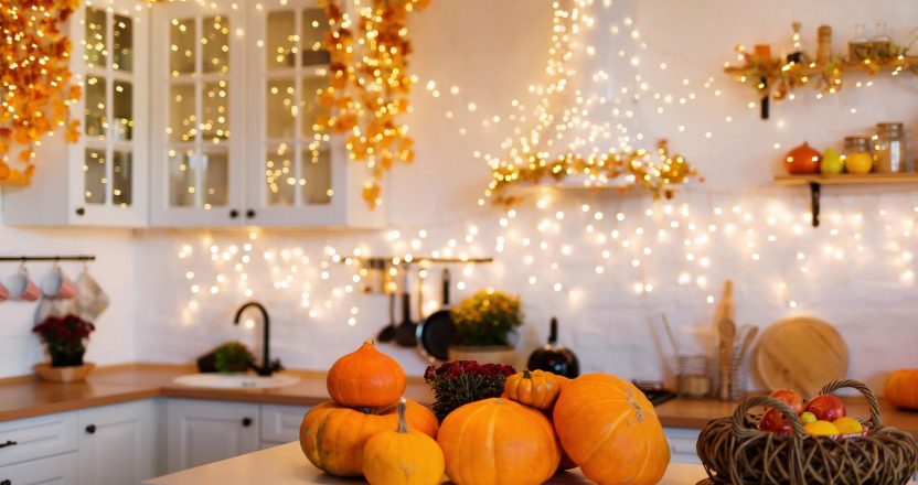 Autumn kitchen interior. Red and yellow leaves and flowers in the vase and pumpkin on light background