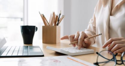 Close up Business woman or accountant using calculator with computer laptop, Business accounting, budget and loan paper at home