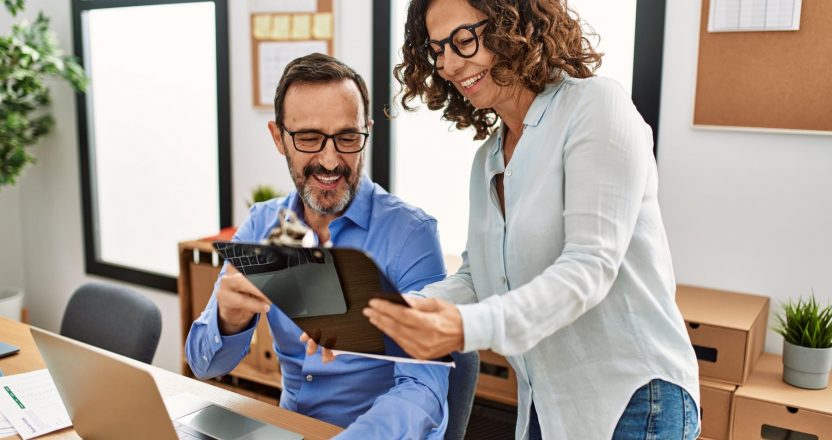 Two middle age business workers smiling happy working at the office.