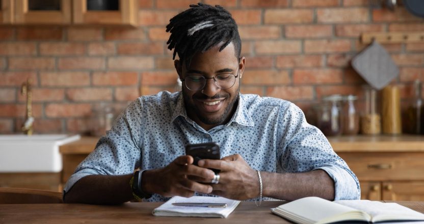 Happy Afro American guy chatting online, checking messages