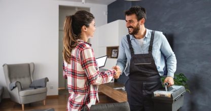 Happy woman shaking hands with repairman. Home interior.