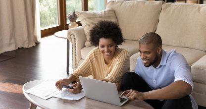 Happy african american family couple analyzing financial paper documents.