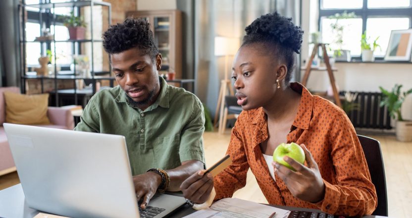Two landlords sitting and reporting their rental income using a laptop.