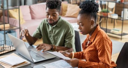 Young confident businessman making presentation to African female with papers