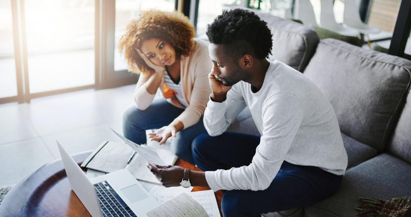 Trying to get their finances in order. Shot of a young couple looking anxious while doing their budget at home.