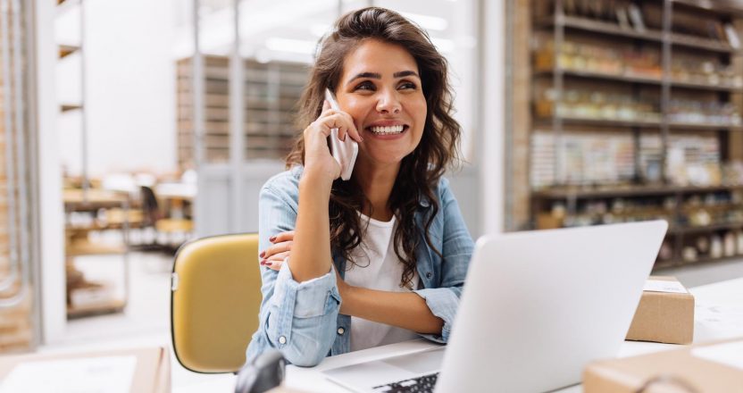 Cheerful businesswoman speaking on the phone in a warehouse