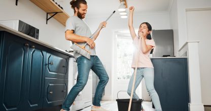 Having fun doing chores, dancing and singing father and daughter cleaning the living room together at home. Carefree, happy and cheerful parent bonding, doing housework and playing with little girl