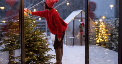 Woman decorates Christmas tree at bacyard
