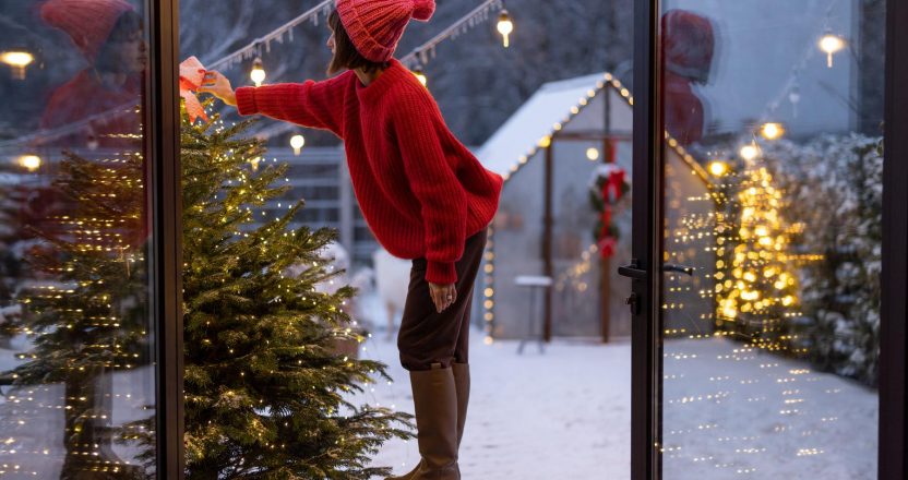 Woman decorates Christmas tree at bacyard