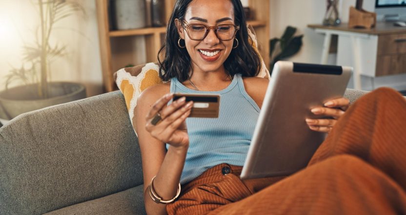 Ecommerce, credit card and woman on a couch, tablet or payment with an order, home or online shopping. Female person, girl or customer on a sofa, technology or buying products with retail or banking