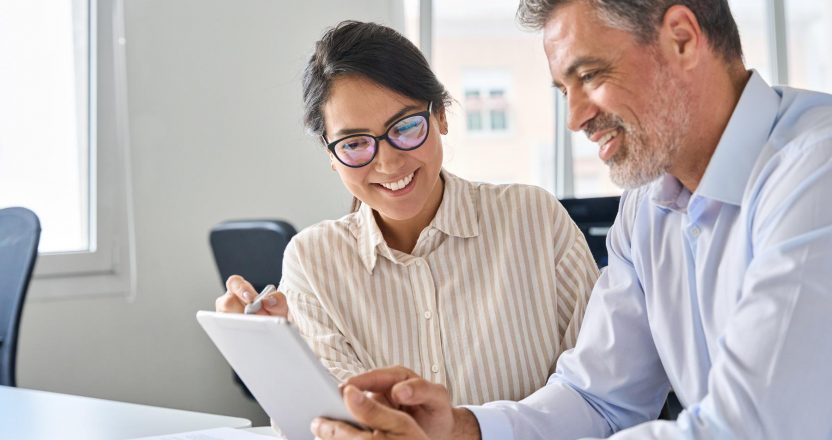 Two happy professional business people workers using digital tablet in office.
