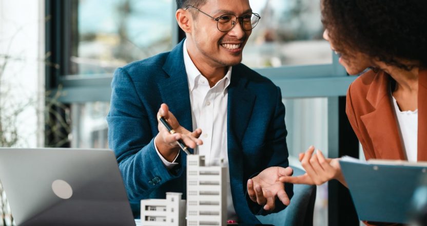 A property manager in a blue suit discusses rental property accounting reports with a landlord.