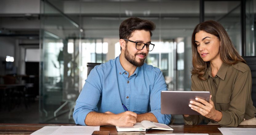 Two people review a guide to rental market trends covering digital payments, listings, and single-family homes on an iPad.