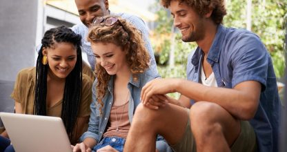 Laptop, education and group of friends on college or school campus together for learning or study. Computer, smile or university project with happy young man and woman students on academy stairs
