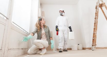Concerned woman at a home renovation site shows a mold problem to a professional worker using products for mold remediation treatment. Concept of wall painting, cleaning, and mold removal service