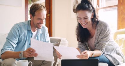 Couple, smile and review with documents at house for tablet, financial planning and debt payment of mortgage. Man, woman and paperwork for budget savings, property insurance and asset management
