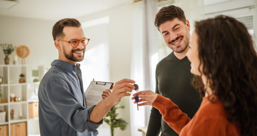 A realtor hands keys to a couple after signing a month-to-month lease in their new home.