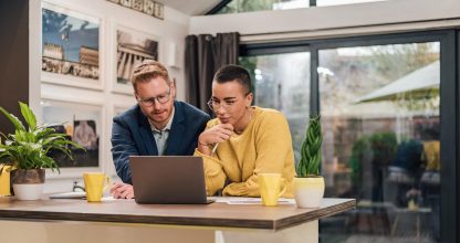 Young successful mixed races couple sitting in living room or ki