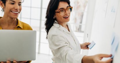 Happy business women creating a to do list using sticky notes