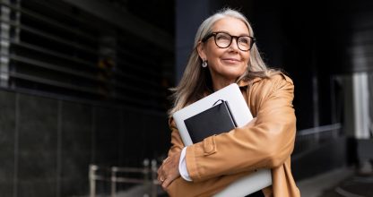 portrait of an elderly businesswoman with a laptop in glasses outside the office, strong and independent woman concept