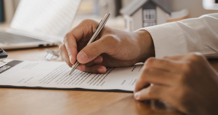Close-up of a person signing a lease agreement after comparing lease vs rent options.