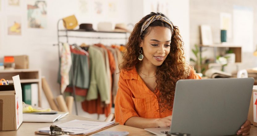 Clipboard, laptop and black woman writing in clothing store working on sales or delivery. Fashion, manager and worker in South Africa in small business, fashion shop and planning schedule on computer