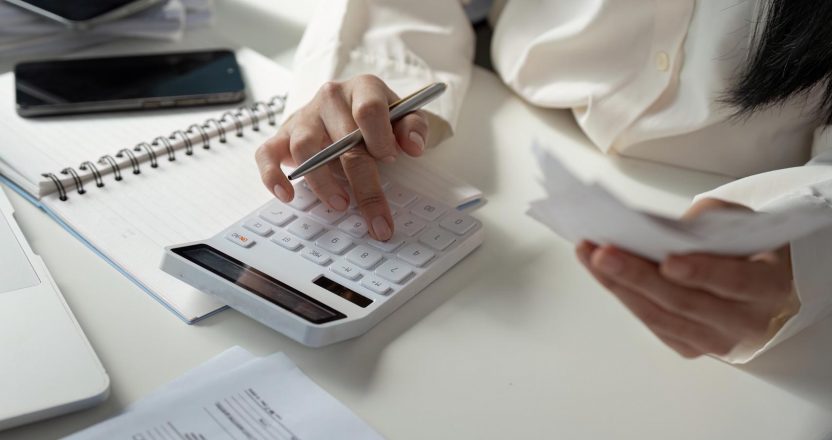Tax Analysis. An individual conducting financial calculations and organizing tax documents at a desk with a calculator and notepad.