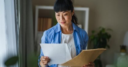 Japanese woman hold mail envelope letter with good news at home