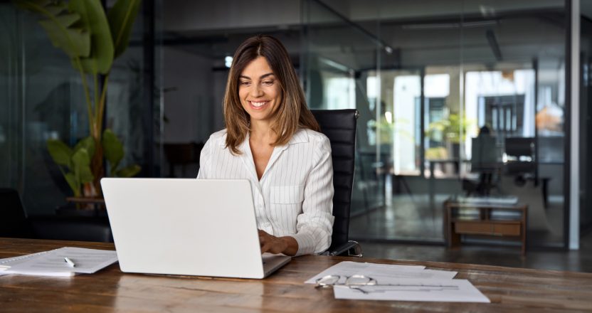 A woman using a laptop checks lease agreements for compliance.