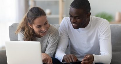Happy smiling mixed race couple calculating domestic bills at home
