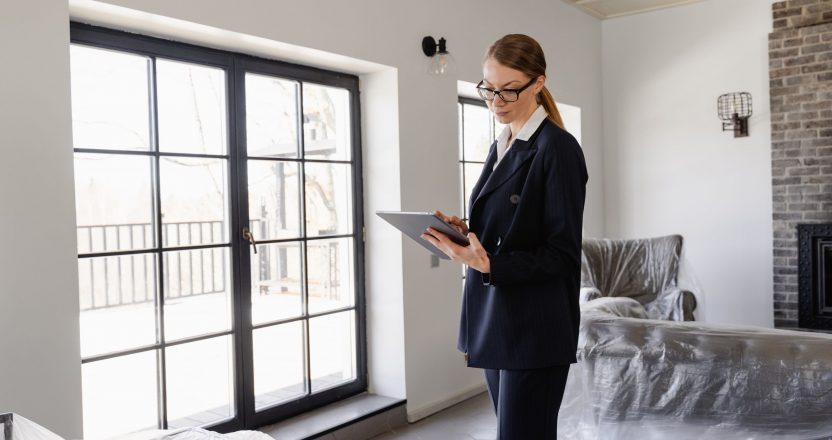 Real estate property manager in a black blazer using a tablet inside a furnished home.
