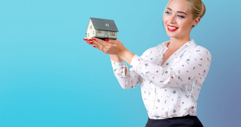 Professional property manager holding a miniature house model, symbolizing real estate and property management.